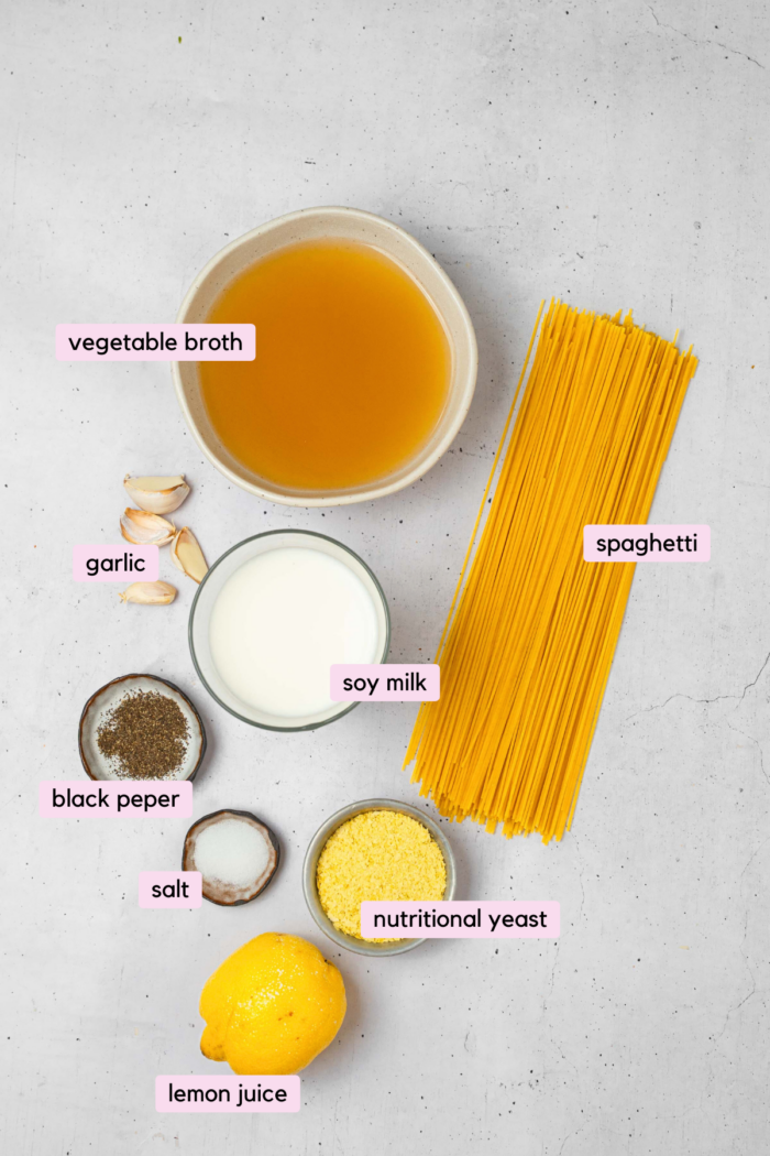 Ingredients for easy vegan alfredo pasta, laid out and labeled on a clear white background.