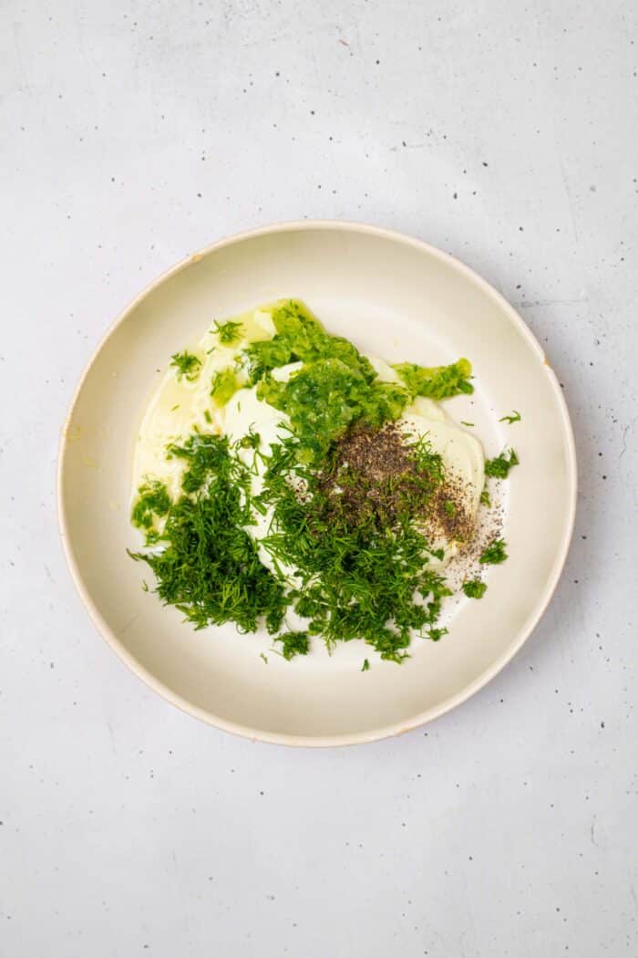 The tzatziki sauce ingredients added to a bowl.