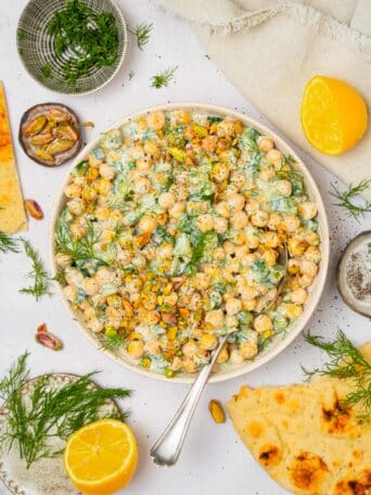 A top down photo of tzatziki chickpea salad in a large shallow salad bowl.