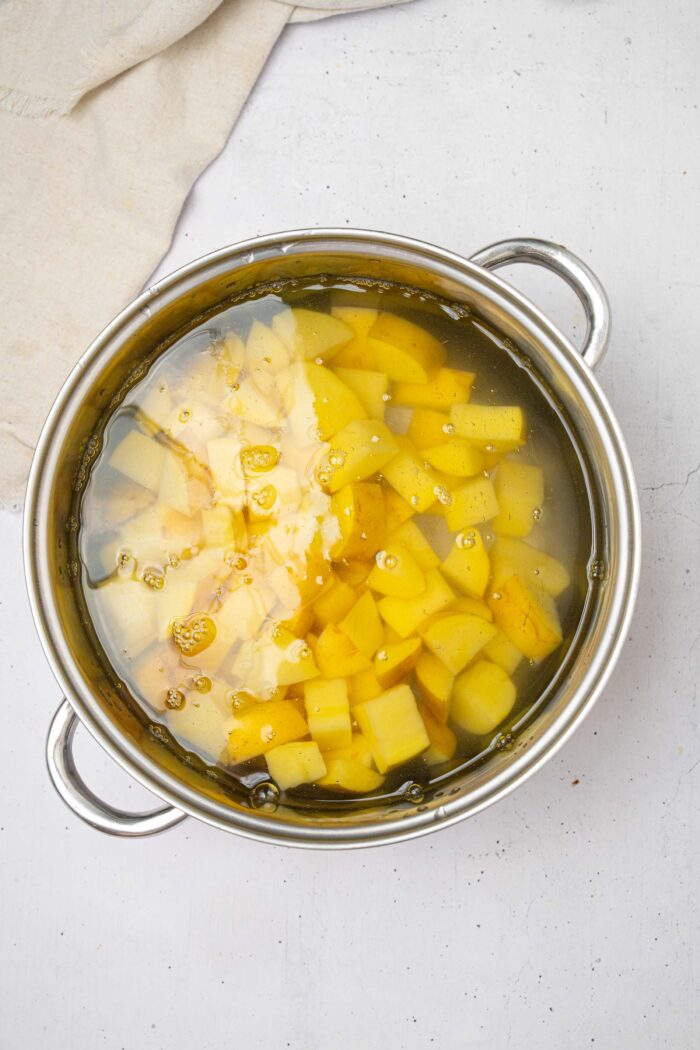 Potatoes in water in a steel pot.