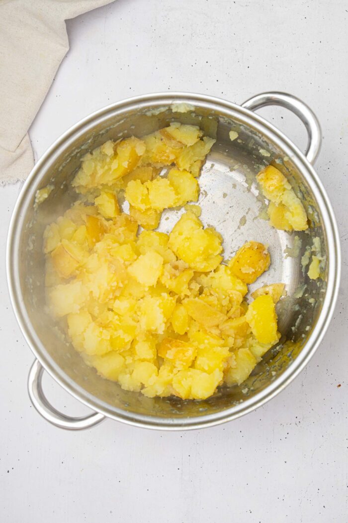After being shaken, the boiled potatoes in a steel pot are fluffy.