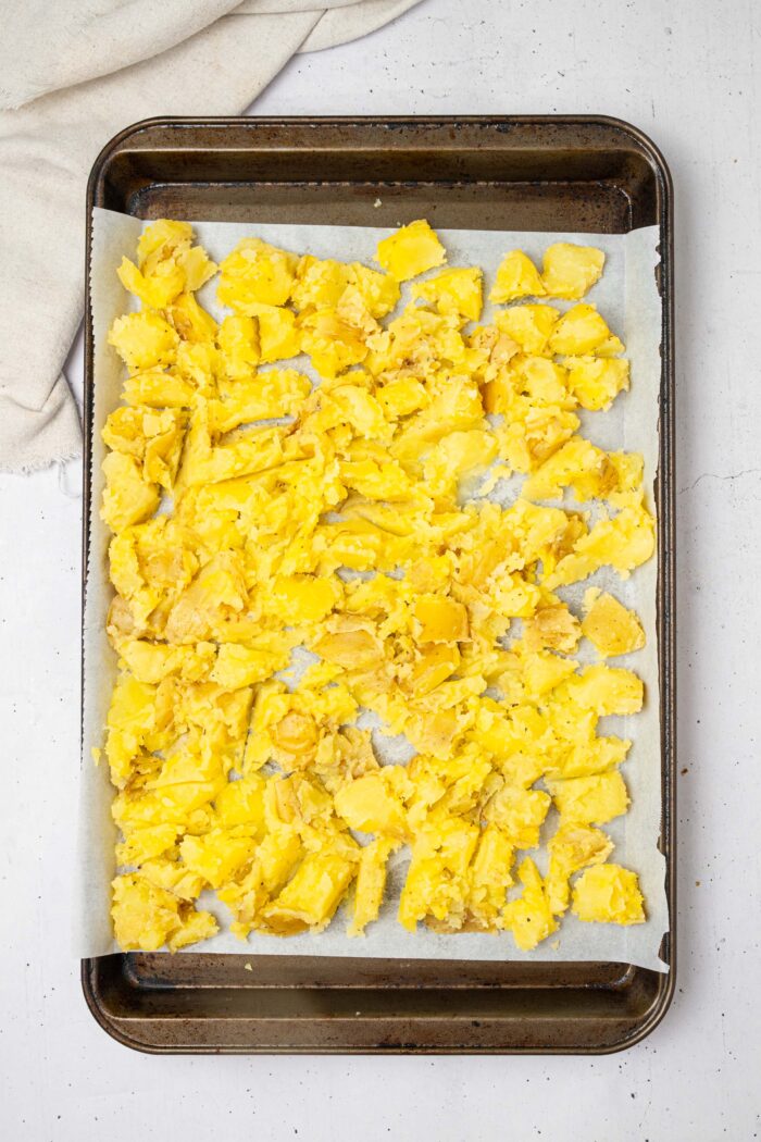 Shaken potatoes with seasonings, laid out in a single layer on a lined sheet pan.