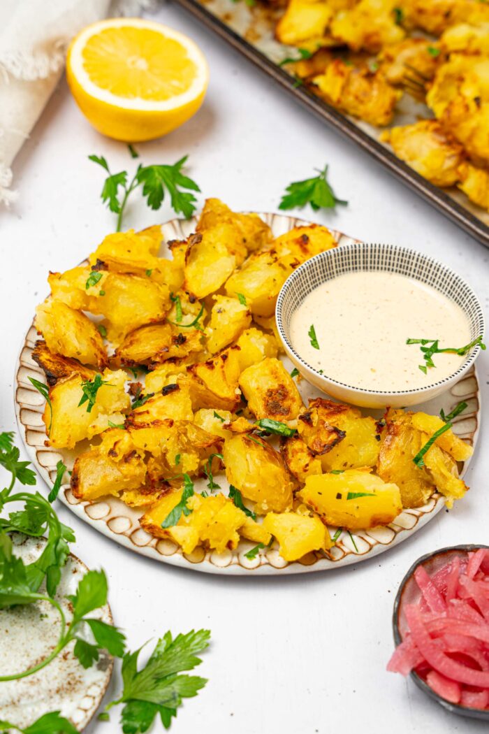 A plate with a serving of shaken potatoes and a dipping sauce on the side.