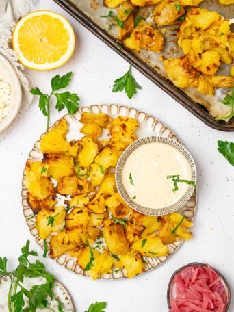 Top down view of shaken potatoes served with dipping sauce.