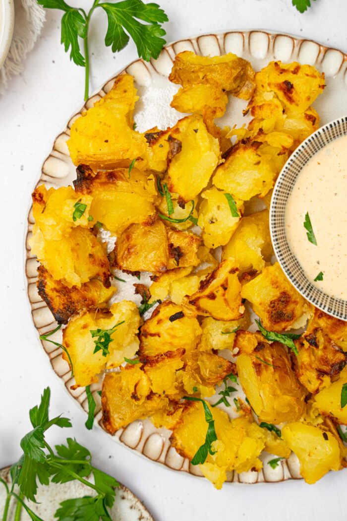 A close up of a plate with shaken potatoes and a side of dipping sauce.