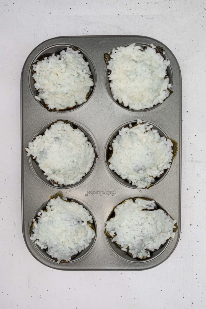 Each nori square with sushi rice, pushed into a muffin tray.
