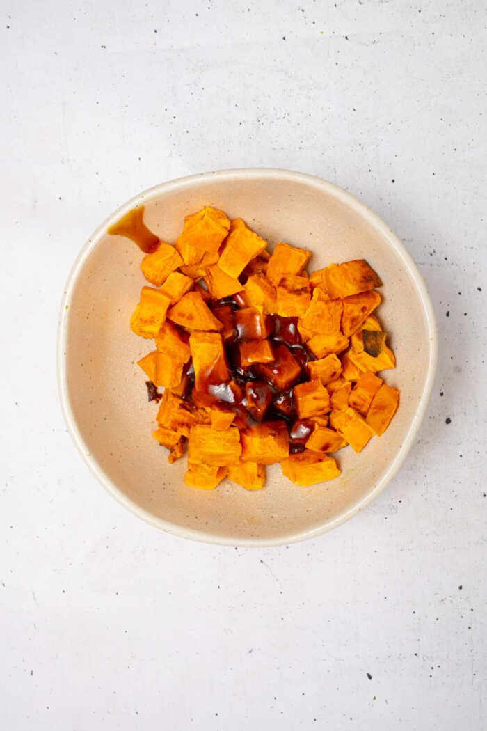 Sweet potatoes with teriyaki sauce, about to be mixed together in a bowl.