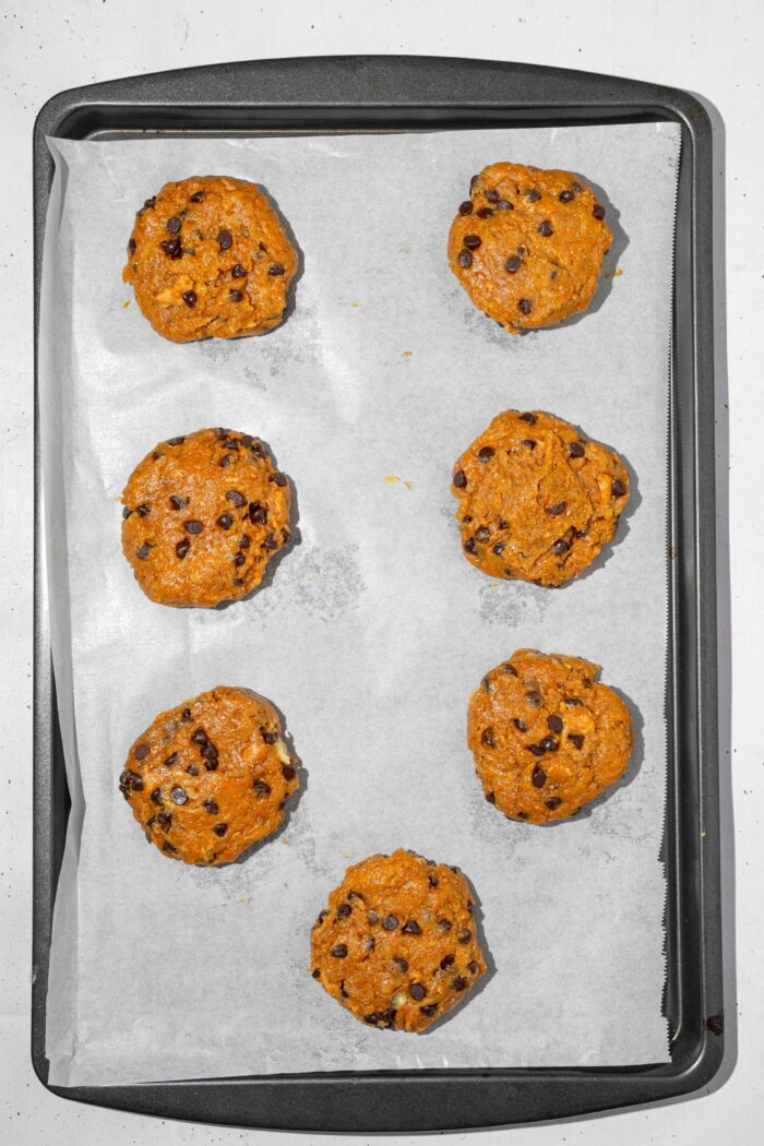 Vegan protein cookies shaped and spread on a baking tray.