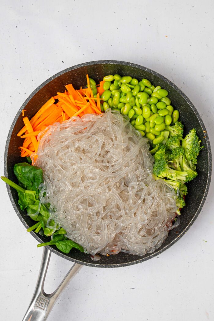 Glass noodles added to the vegetables in the skillet.