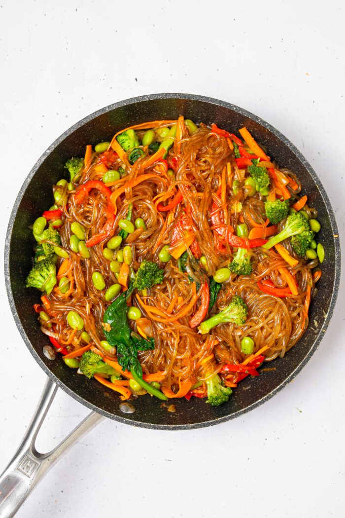 While cooking in the skillet, glass noodle stir fry is mixed together.