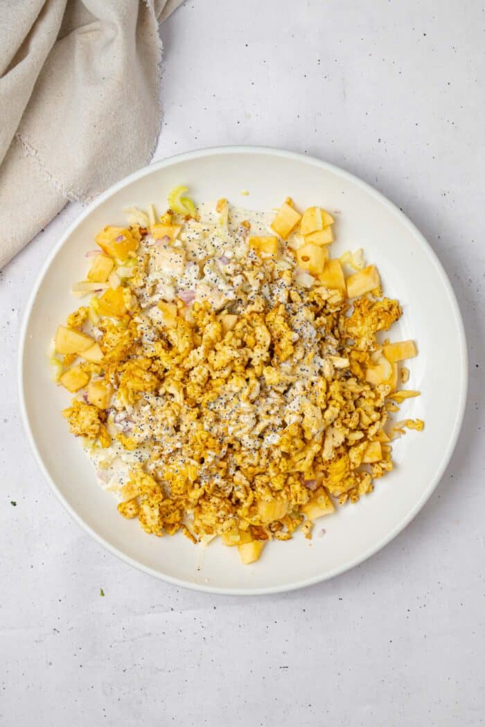 Tofu added to the rest of the shredded tofu salad ingredients in a mixing bowl.