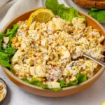 A bowl of shredded tofu salad with some fresh lettuce and a wedge of lemon for brightness.