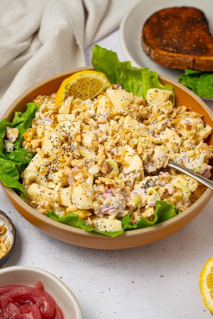 A bowl of shredded tofu salad with some fresh lettuce and a wedge of lemon for brightness.