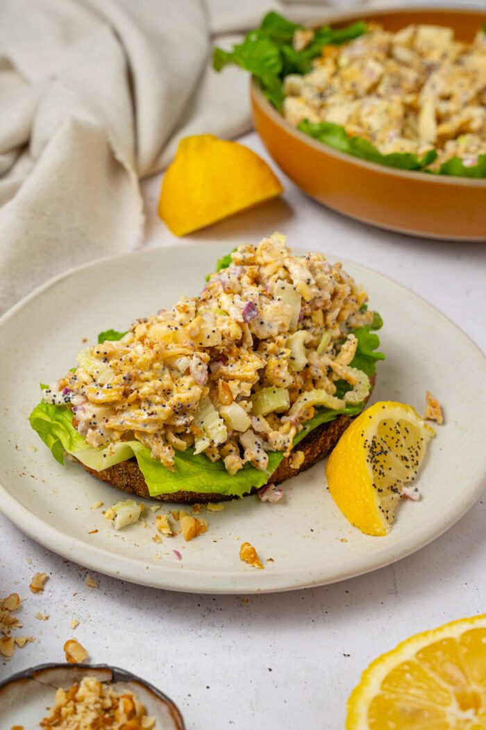 A shot of shredded tofu salad sandwich served with whole wheat bread and some lettuce.