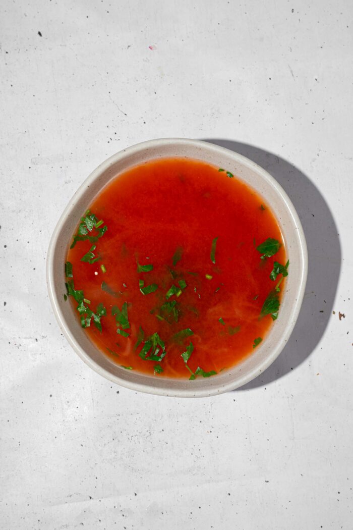 The sauce for the vegan cabbage rolls, made with vegetable broth, tomato paste, and fresh parsley.
