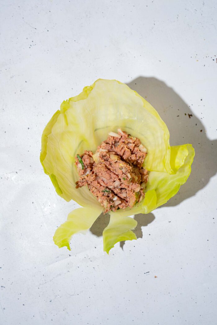 Two heaping tablespoons of filling placed at the center of a cabbage leaf.