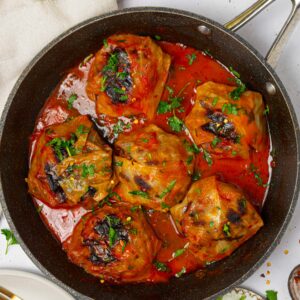 A pan with vegan cabbage rolls served with fresh herbs.
