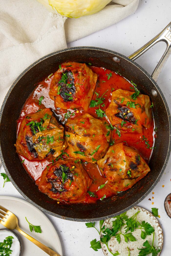 A pan with vegan cabbage rolls served with fresh herbs.