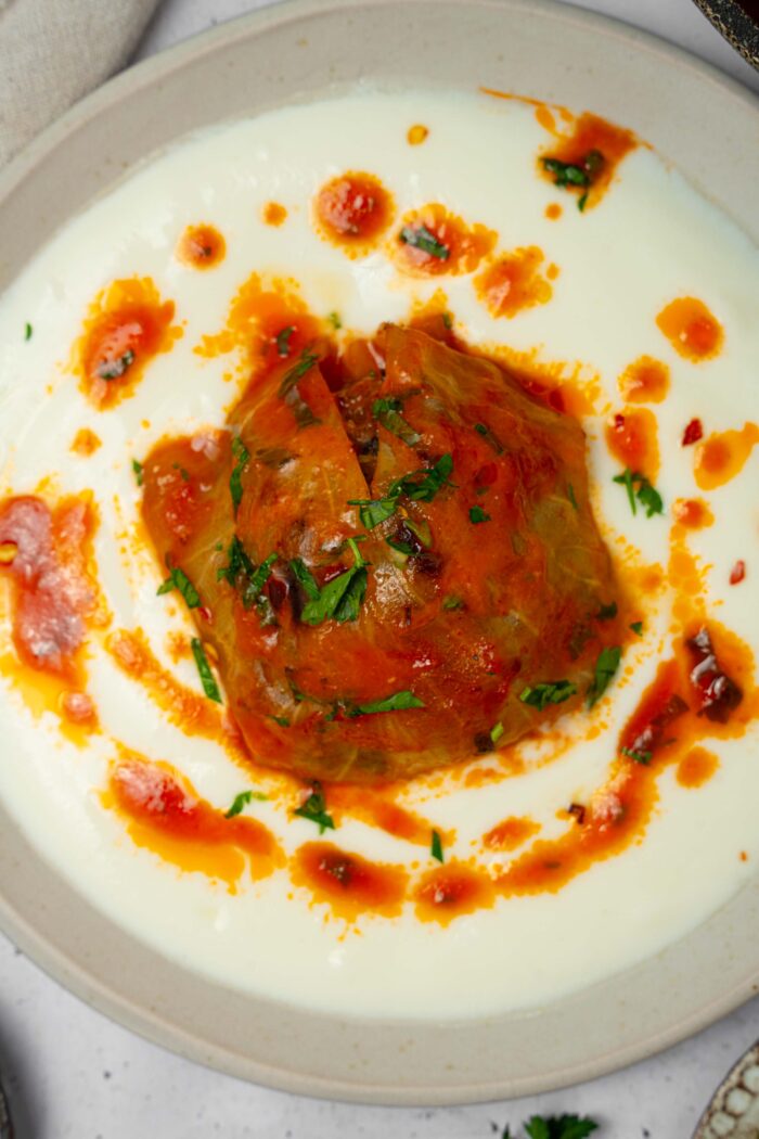 A top down view of a vegan cabbage roll with tomato sauce on a plate.