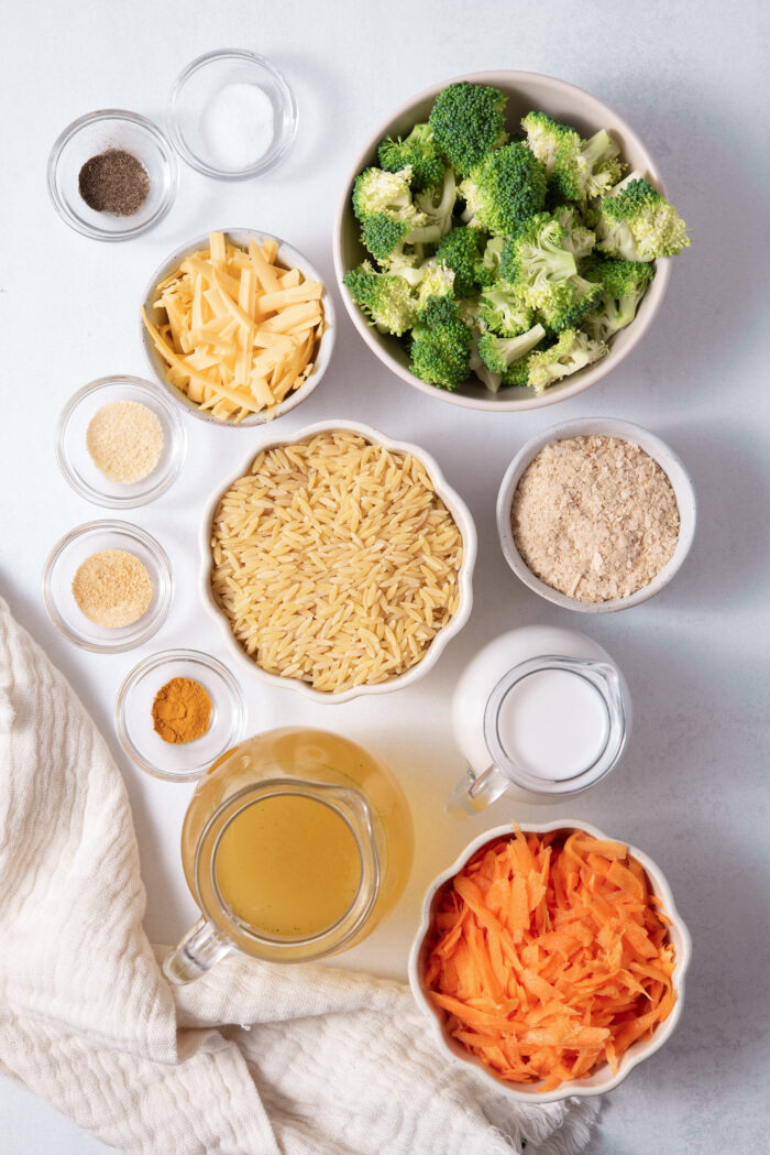 The ingredients for the vegan broccoli cheddar orzo casserole, laid out on a clear background.