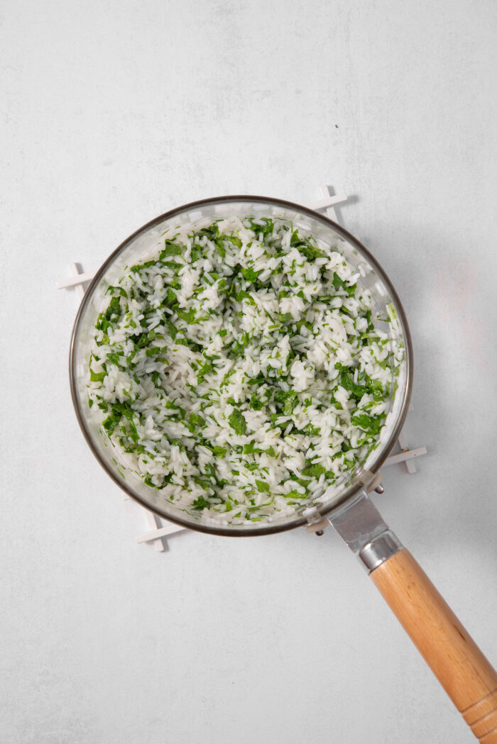 A pan with cooked rice and cilantro mixed together.