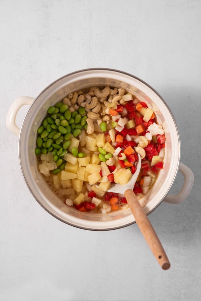 The vegetables and pineapple mixed together in a pan where they will cook.