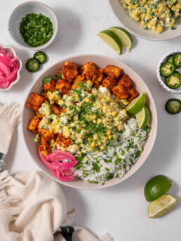 A serving of street corn salad with herb rice and spicy tofu cubes.