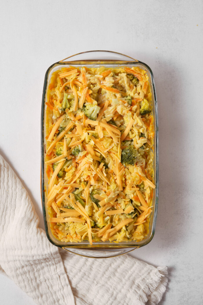 Vegan shredded cheese spread across the vegan broccoli cheddar orzo as the final step in the cooking process.