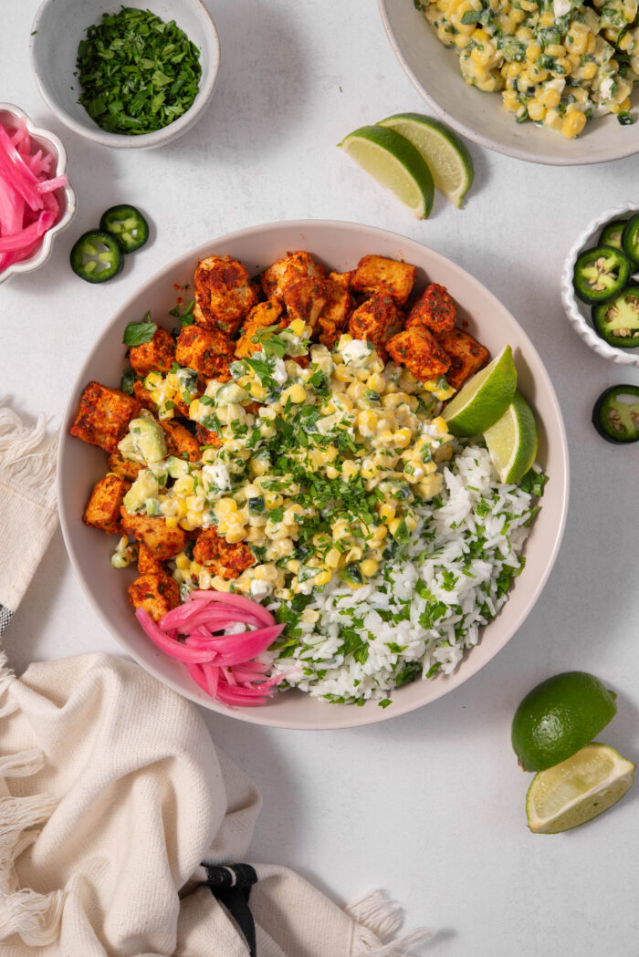A serving of street corn salad with herb rice and spicy tofu cubes.