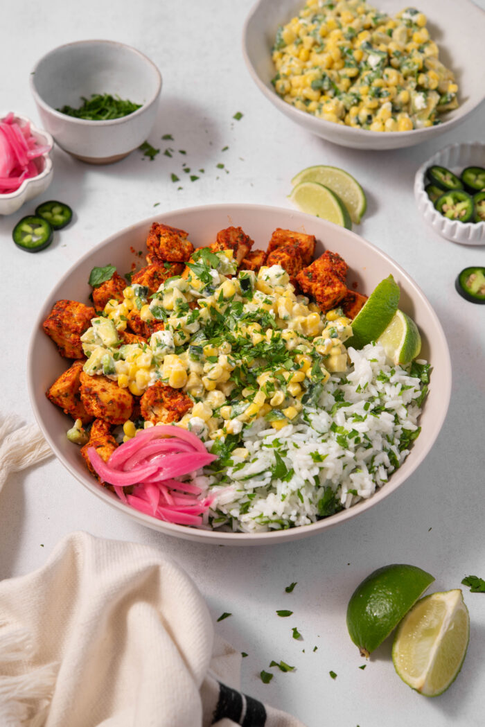A bowl of street corn salad with rice, spicy tofu and pickled red onions.
