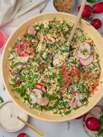 A bowl of herby ranch couscous salad mixed together with the vegan ranch dressing.