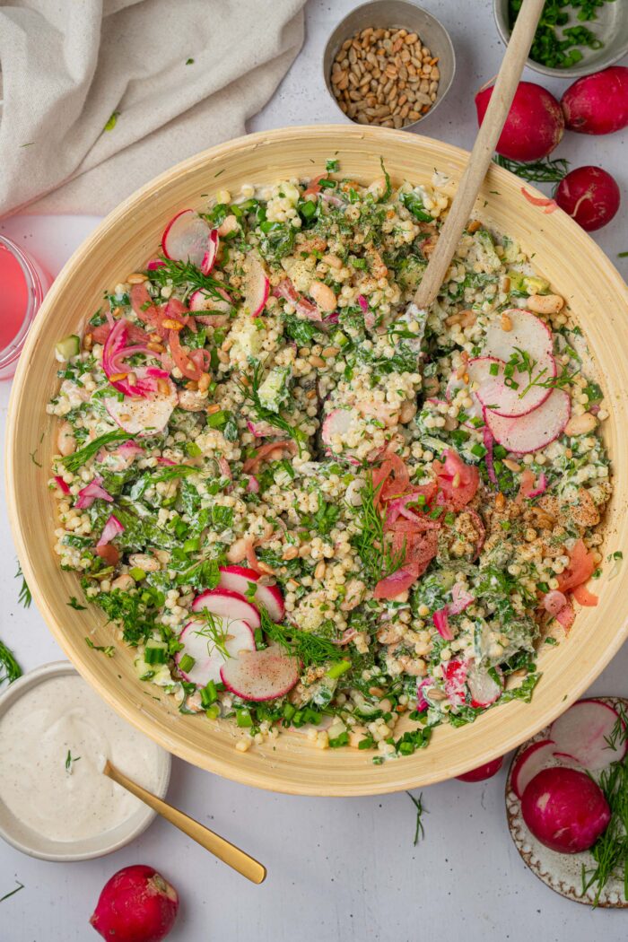 A bowl of herby ranch couscous salad mixed together with the vegan ranch dressing.