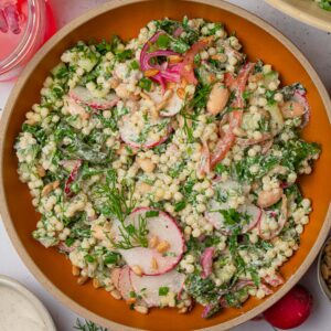 Top down view of herby ranch couscous salad served in a bowl with fresh dill.