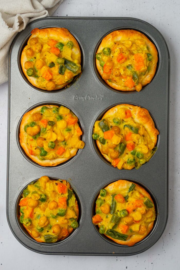 Six mini chickpea pot pies freshly out of the oven, still in the muffin tray.