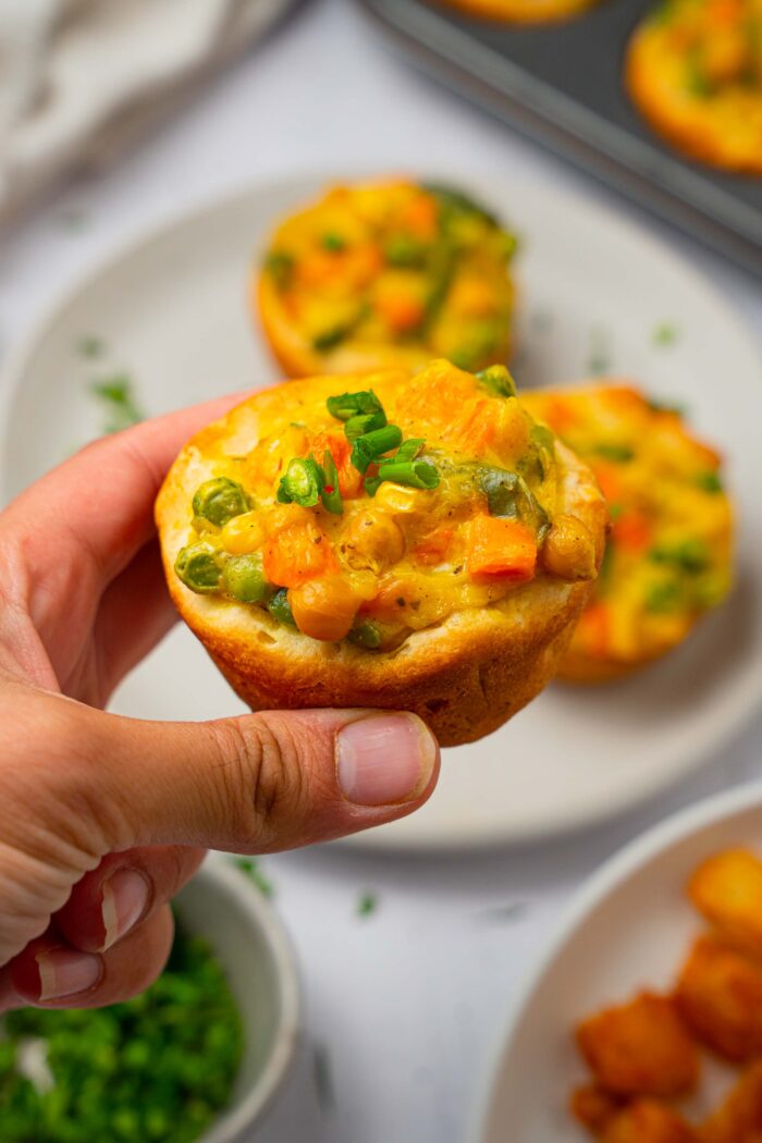 A hand holding up one of mini chickpea pot pies to the camera.