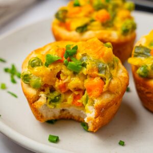 A close up of mini chickpea pot pies with a bite taken out of one of them.