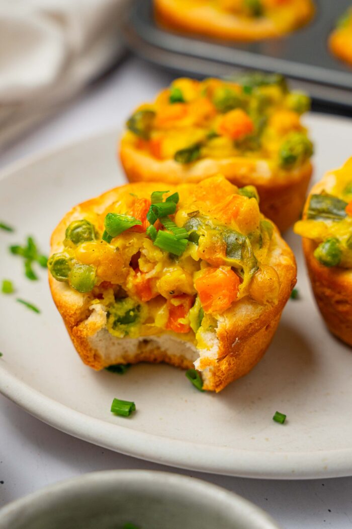 A close up of mini chickpea pot pies with a bite taken out of one of them.