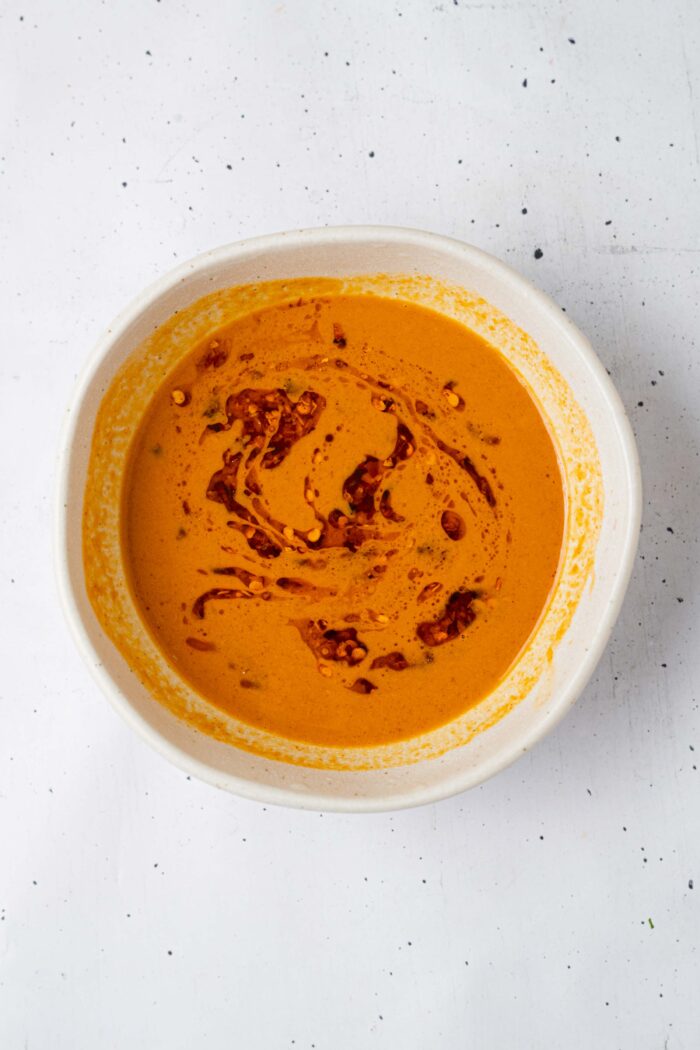 A fully mixed peanut pasta salad dressing, with streaks of chili oil visible throughout.
