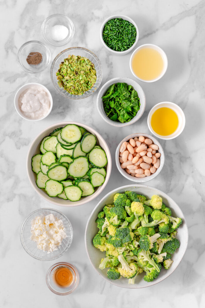 The ingredients for the broccoli cucumber salad laid out and labeled on a light background.