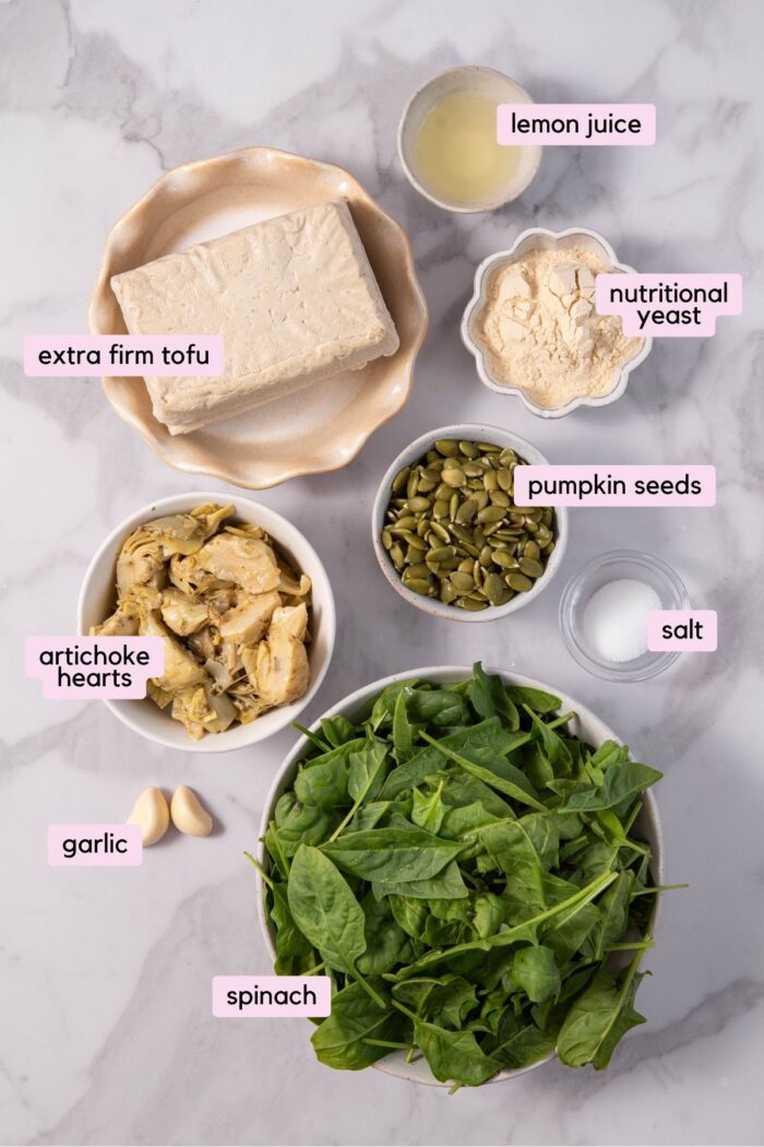 The ingredients for the vegan spinach artichoke dip, laid out and labeled on a light clear background.