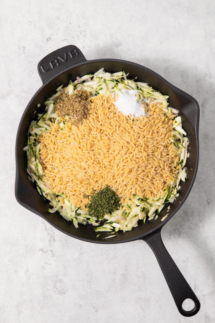 Orzo and seasonings added to the cast iron pan with the zucchini.