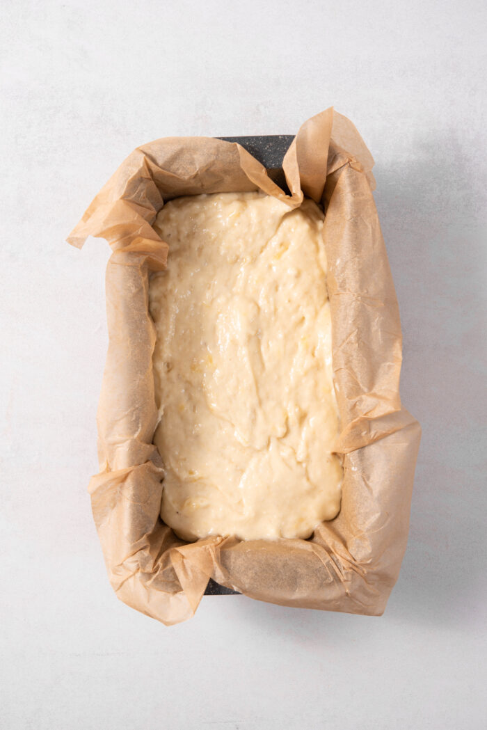 The banana bread batter in a lined loaf tin.