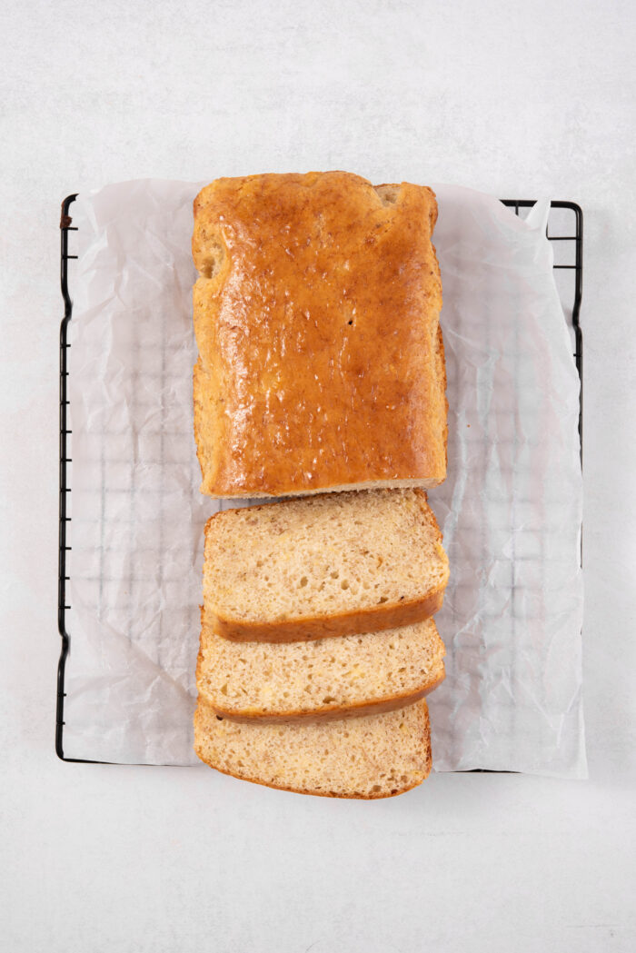 The freshly baked easy vegan banana bread on a cooling rack, parly sliced.