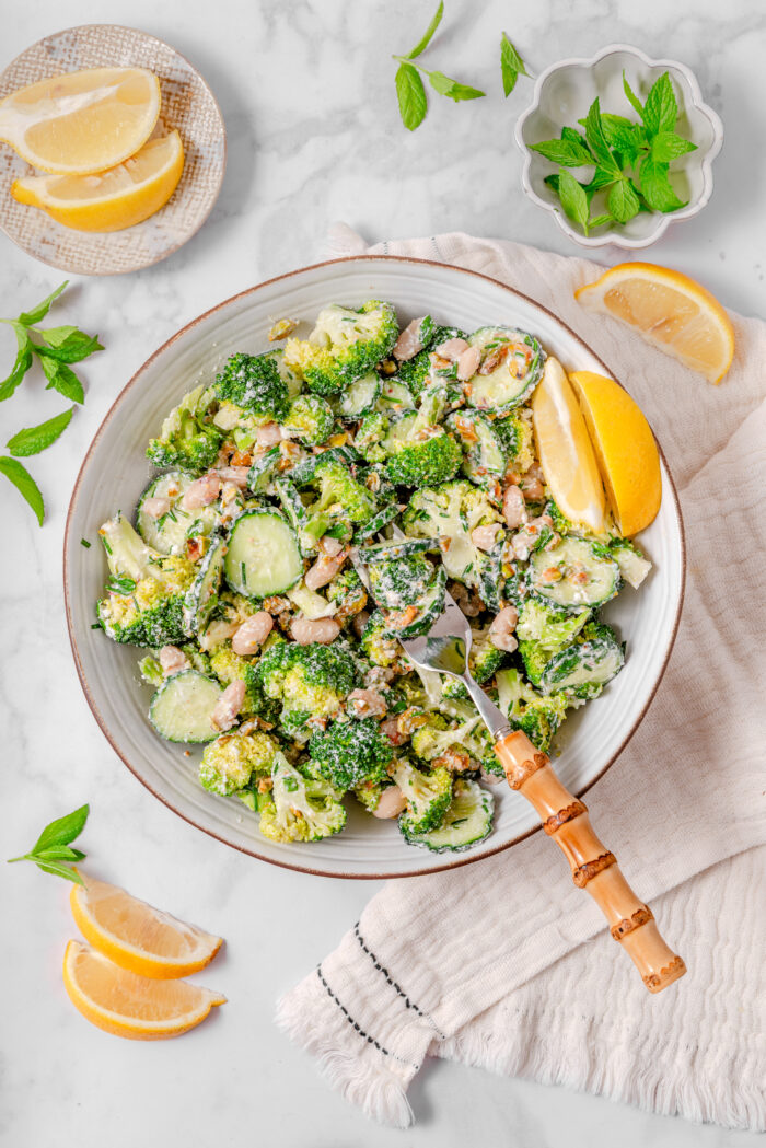 A top down shot of broccoli cucumber salad with a fork sticking out of a bowl.