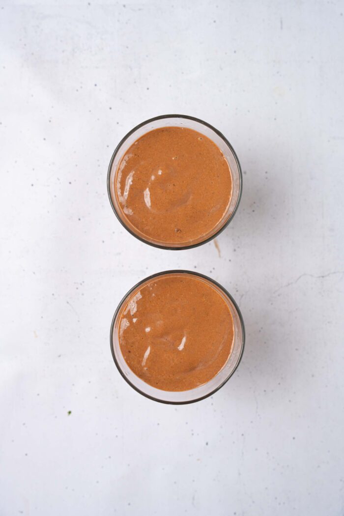 The blended chocolate chia pudding split between cups for meal prep.
