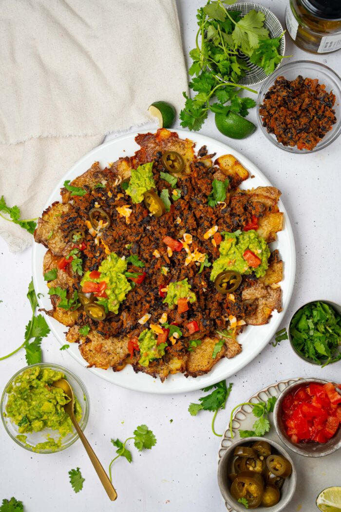 A platter of smashed potato nachos served with black beans, and any of your favorite toppings.
