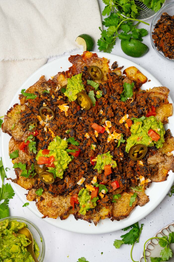 Top down view of the smashed potato nachos with guac, tomatoes, and jalapenos.
