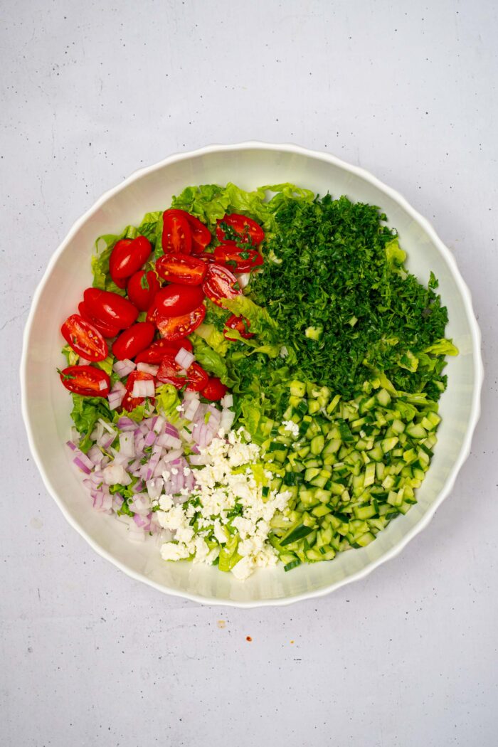 Finely chopped veggies and greens in a large salad bowl.