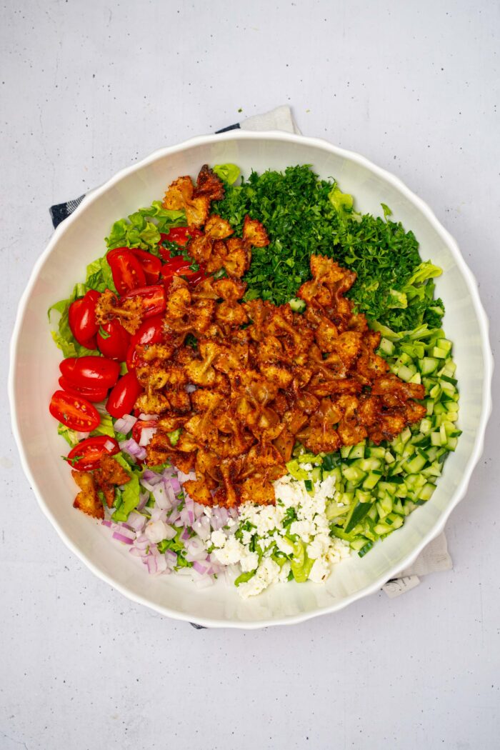 The crispy baked pasta added to the rest of the ingredients in the large salad bowl.