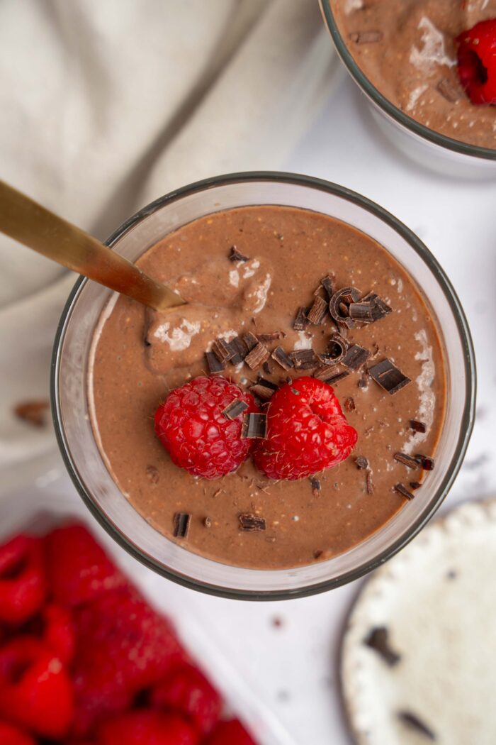A top down view of a blended chocolate chia pudding cup with a spoon sticking out.